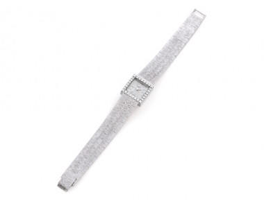 Piaget lady’s square 18K white gold wristwatch with diamond-set bezel, textured dial with baton numerals, concealed crown, and integrated textured bracelet