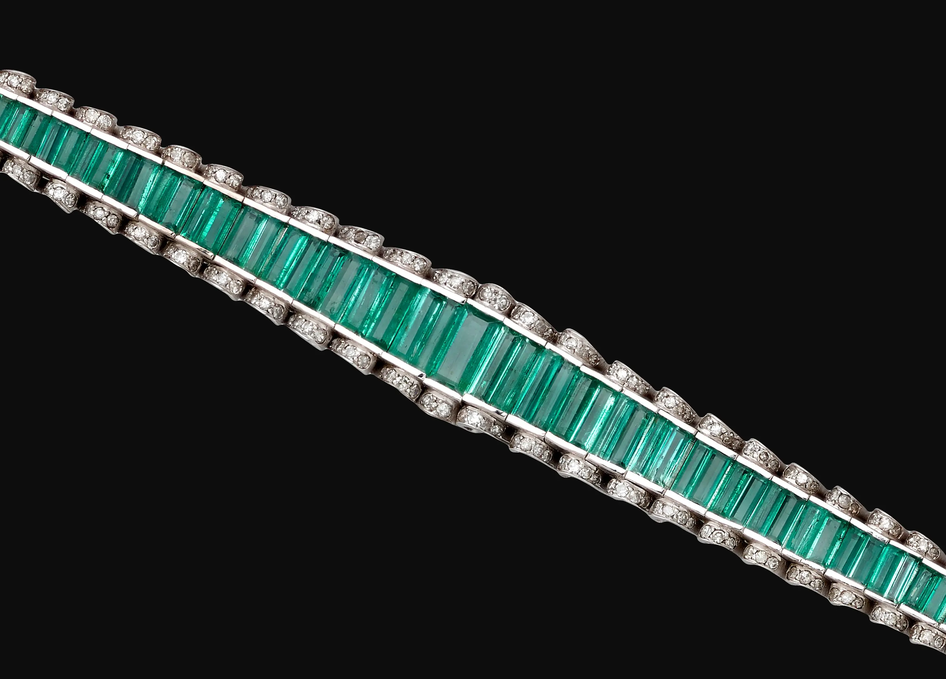Palladium bracelet set with a continuous line of octagonal step-cut Colombian emeralds bordered by colorless diamonds, 7-inch length