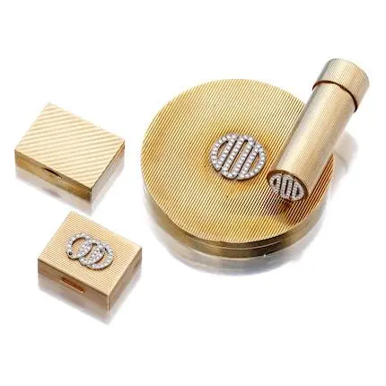 Group of mid-century 14K gold vanity accessories—ridged circular powder compact with single-cut diamond geometric panel, lipstick case, and two matching pieces.